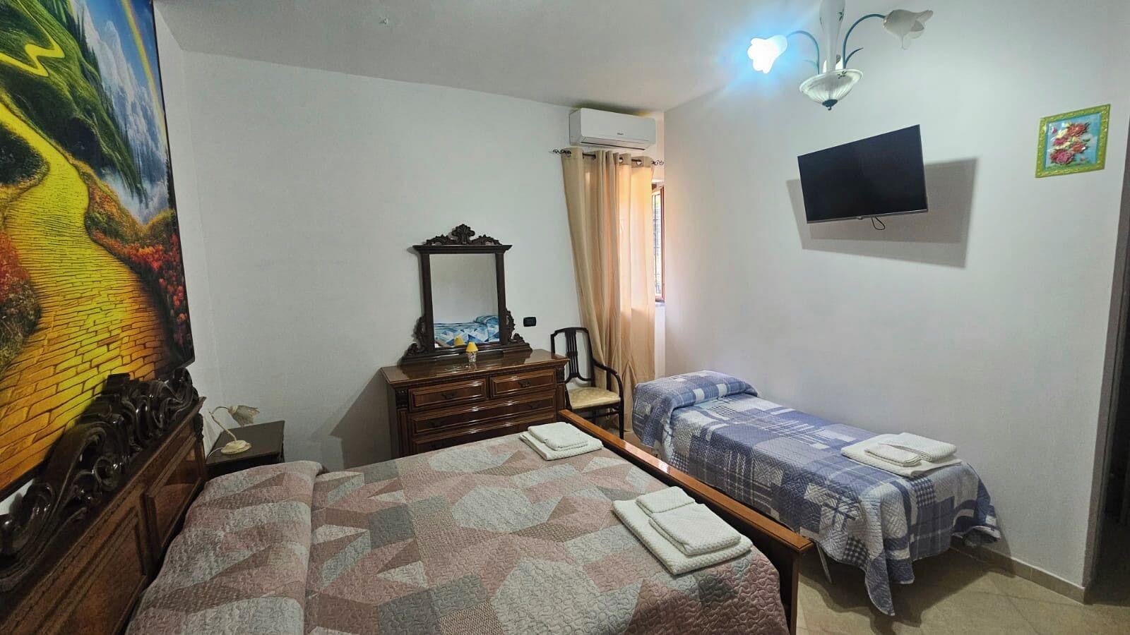 Un dormitorio con dos camas, un aparador, un televisor y un cuadro.