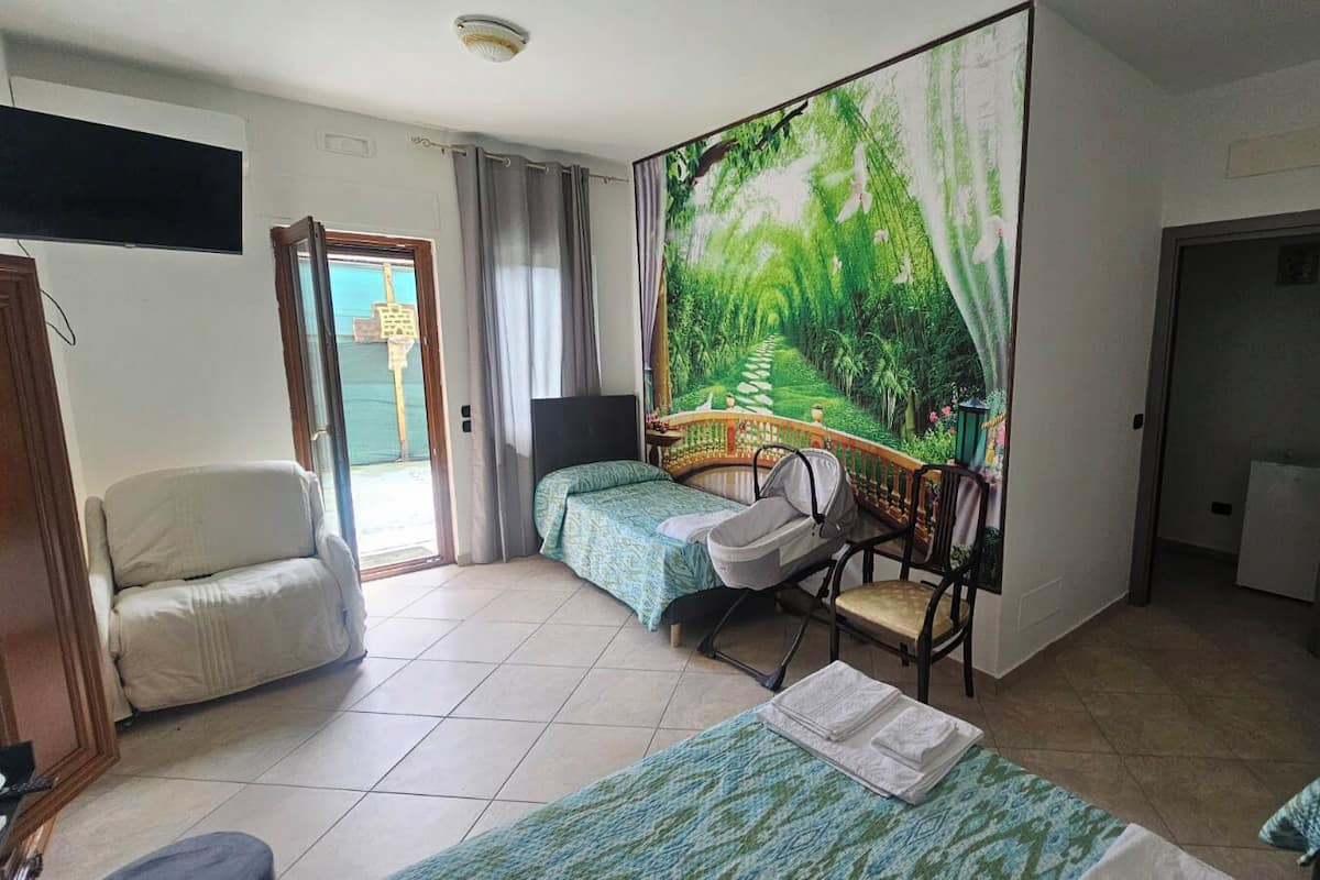 A hotel room with two beds, a chair, a desk, a large window with a view, and a door leading to a balcony.