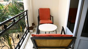 A balcony with a round table and two chairs, one with a red cushion and the other with a yellow cushion. - KIGALI BRIGHT HOMES AND HOTEL (Kigali)