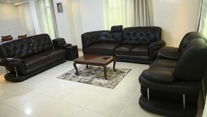 A living room with a sectional sofa, a coffee table, and a chair. - KIGALI BRIGHT HOMES AND HOTEL (Kigali)