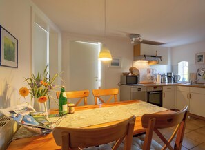 Una cucina con mobili in legno, un tavolo da pranzo con sedie, un forno a microonde e diversi elettrodomestici.