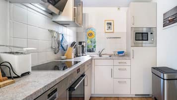 A compact kitchen with white cabinetry, a built-in oven, a microwave, and a toaster.