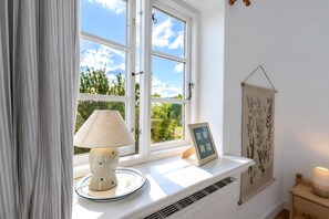 A room with a window, a lamp, a framed picture, and a wall hanging. - Nordermühle Apartment with Shared Garden, Terrace and Wi-Fi (Pellworm)