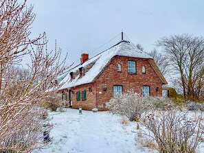 Tiilitalo, jossa on jyrkkästi kallistuva katto, useita ikkunoita ja savupiippu.