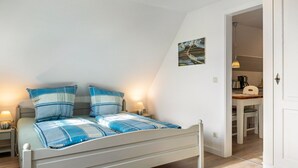 Une chambre à coucher avec un lit, des tables de chevet, une lampe et un tableau au mur.