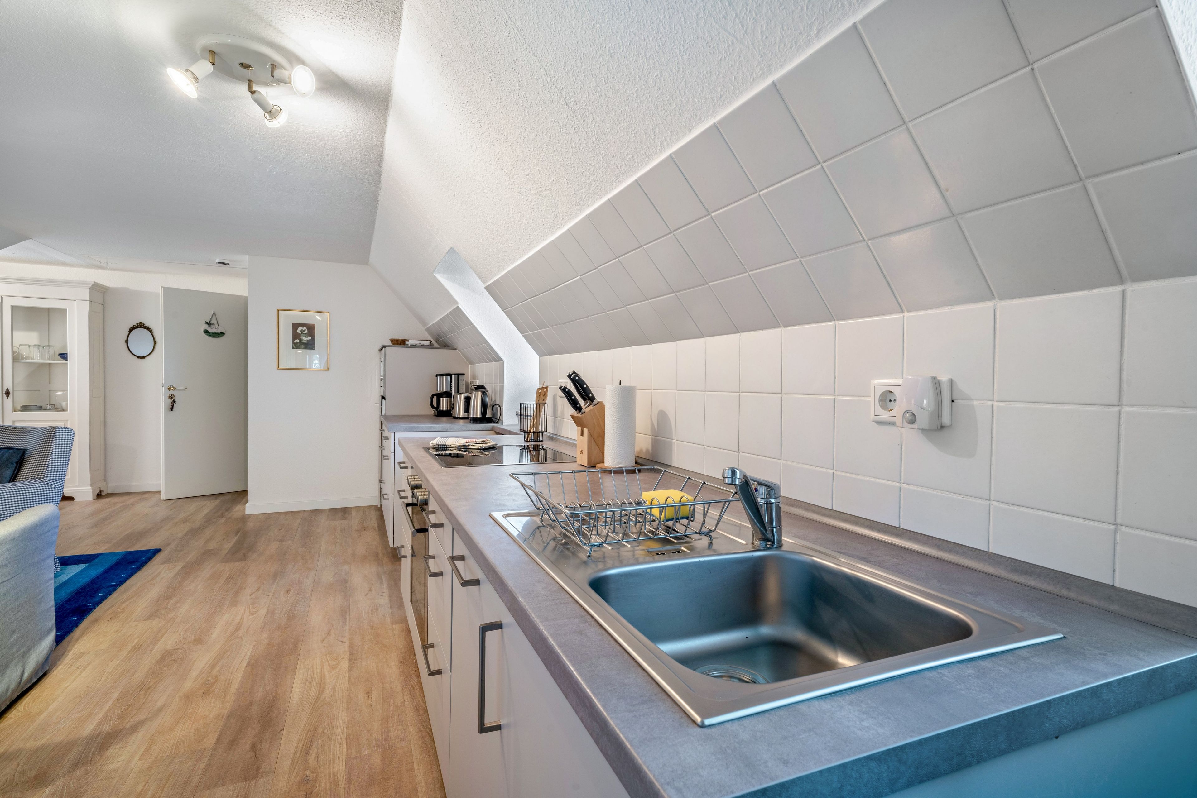 Eine moderne Küche mit eingebautem Geschirrspüler, einer Edelstahlspüle und einer Kaffeemaschine.