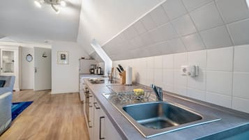 Eine moderne Küche mit eingebautem Geschirrspüler, einer Edelstahlspüle und einer Kaffeemaschine.