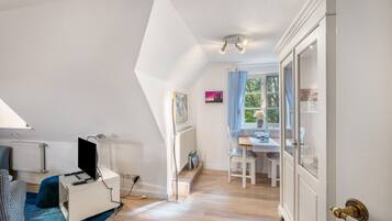 Ein Zimmer mit Schreibtisch, Stuhl und Heizkörper.