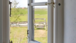 An open window with a view of a grassy field and a wooden structure outside. - Apartment Vogelkoje with Shared Garden and Wi-Fi (Pellworm)