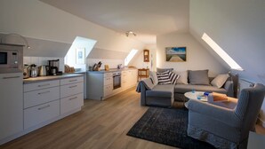 A modern loft apartment with a kitchen, dining area, and living room. - Apartment Vogelkoje with Shared Garden and Wi-Fi (Pellworm)
