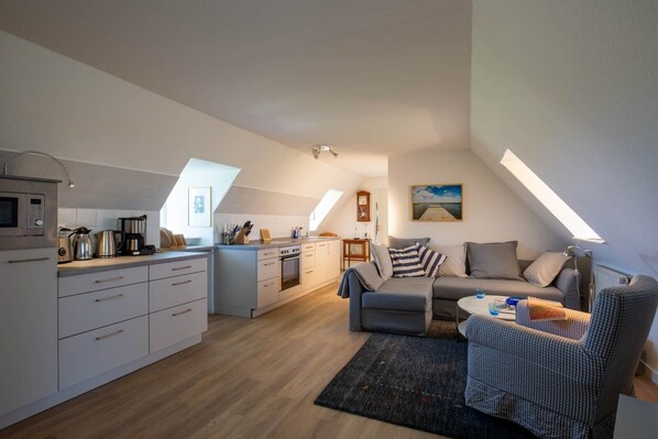 A modern loft apartment with a kitchen, dining area, and living room. - Apartment Vogelkoje with Shared Garden and Wi-Fi (Pellworm)