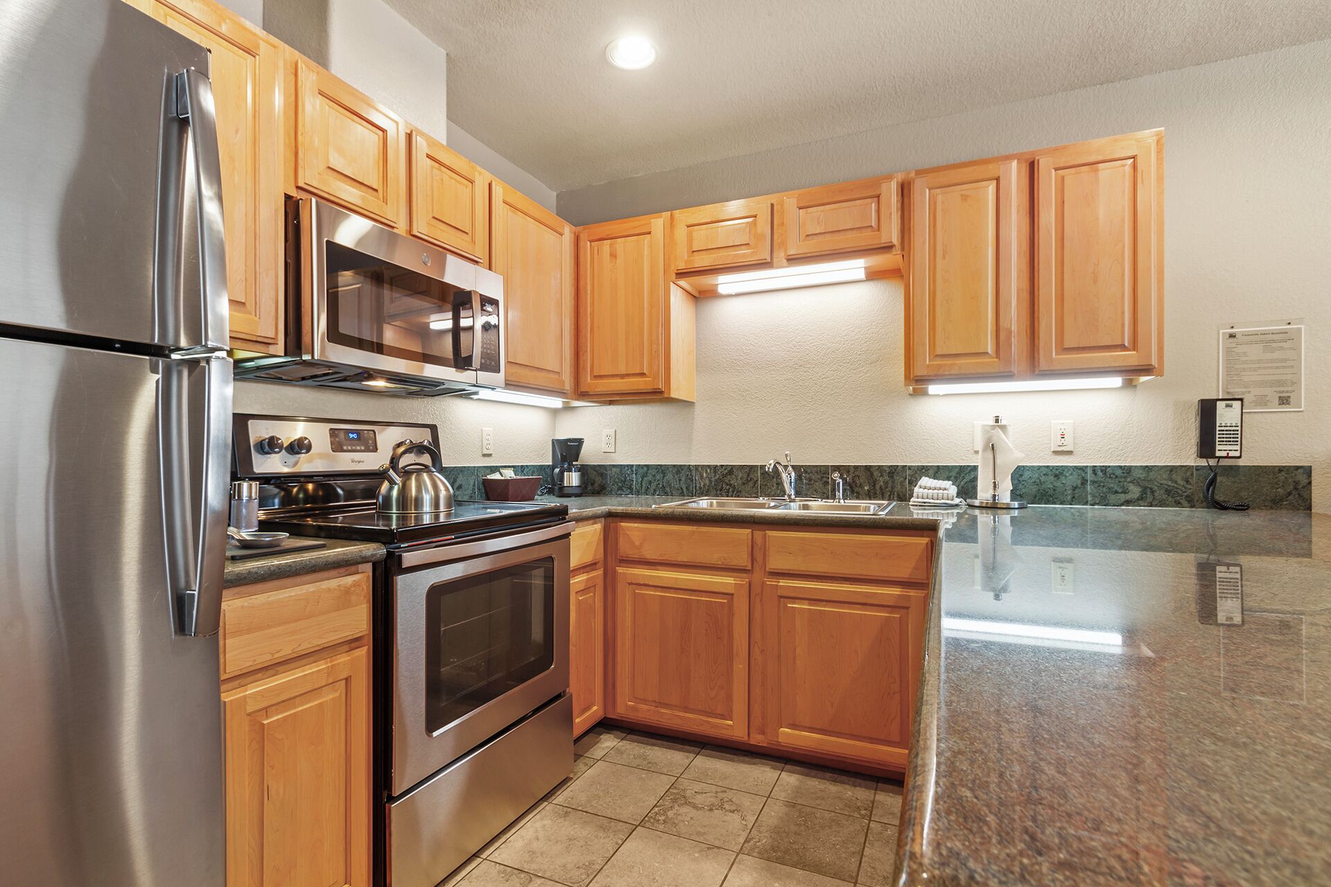 A kitchen with wooden cabinets, stainless steel appliances, granite countertops, and a built-in oven.