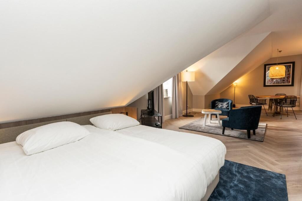 Een hotelkamer met twee bedden, een bureau, een stoel en een eettafel.