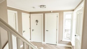 Ein Flur mit drei weißen Türen, davon eine mit der Nummer 2, und einer Treppe, die zu einer anderen Etage führt.