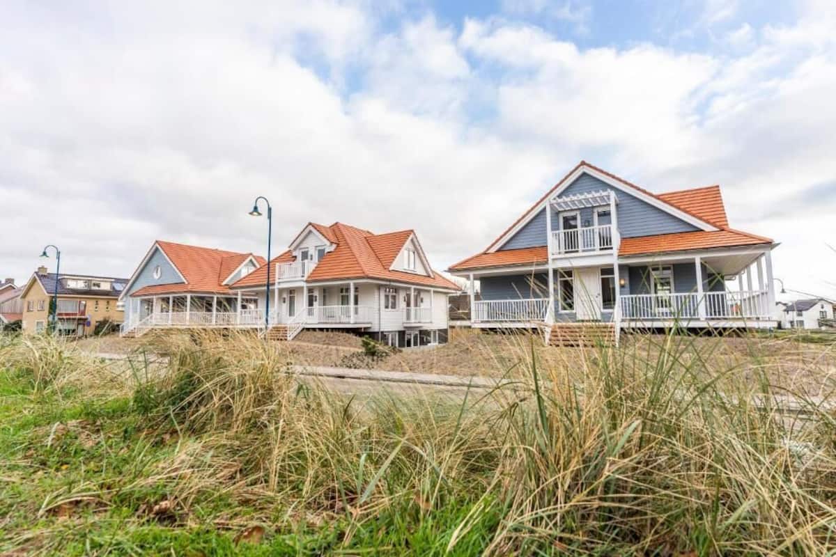 Propiedad frente al mar con varias casas, techos a dos aguas y barandillas blancas.
