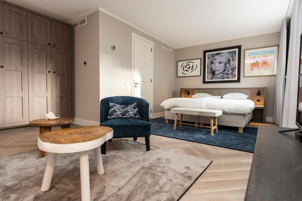 Een hotelkamer met een bed, een stoel, een klein tafeltje en een kledingkast.