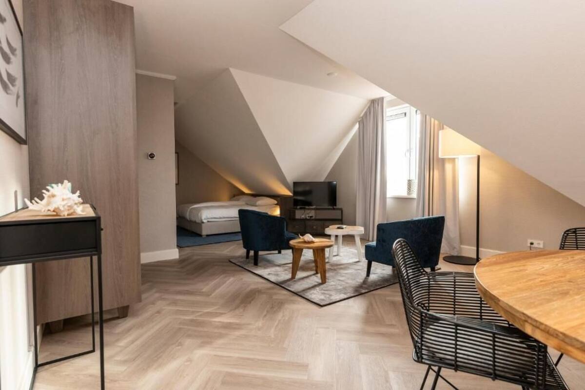 Un dormitorio tipo loft moderno con techo inclinado, una mesa de comedor de madera y una zona de estar acogedora.