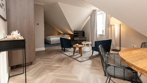 Ein modernes Schlafzimmer im Loft-Stil mit schrägem Dach, einem Holzesstisch und einer gemütlichen Sitzecke.