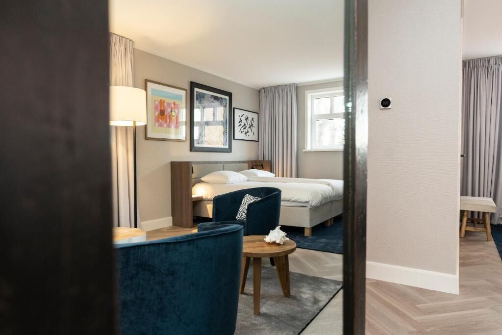 A hotel room with a bed, bedside table, lamp, and a chair.
