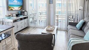 Ett modernt vardagsrum med en soffa, fåtölj, TV och matplats.