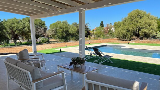 An outdoor patio with white furniture, a pool, and a view of trees and a lawn. - Villa Vittoria, brand new with pool and garden, near the sea, in Cinisi (Palermo)