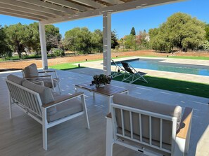 An outdoor patio with white furniture, a pool, and a view of trees and a lawn. - Villa Vittoria, a new villa with a pool and garden, near the sea, in Cinisi (Palermo)