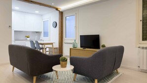 A modern living room with two grey sofas, a small round table, and a TV on a wooden stand. - Usandizaga | The Rentals Collection (San Sebastián/Donostia)