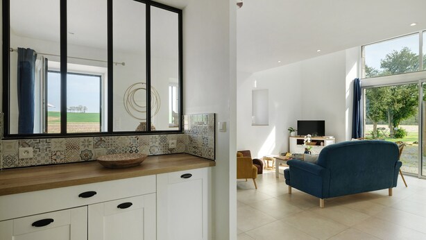 Una cocina moderna con un espejo grande, armarios blancos y un salpicadero decorativo de azulejos.