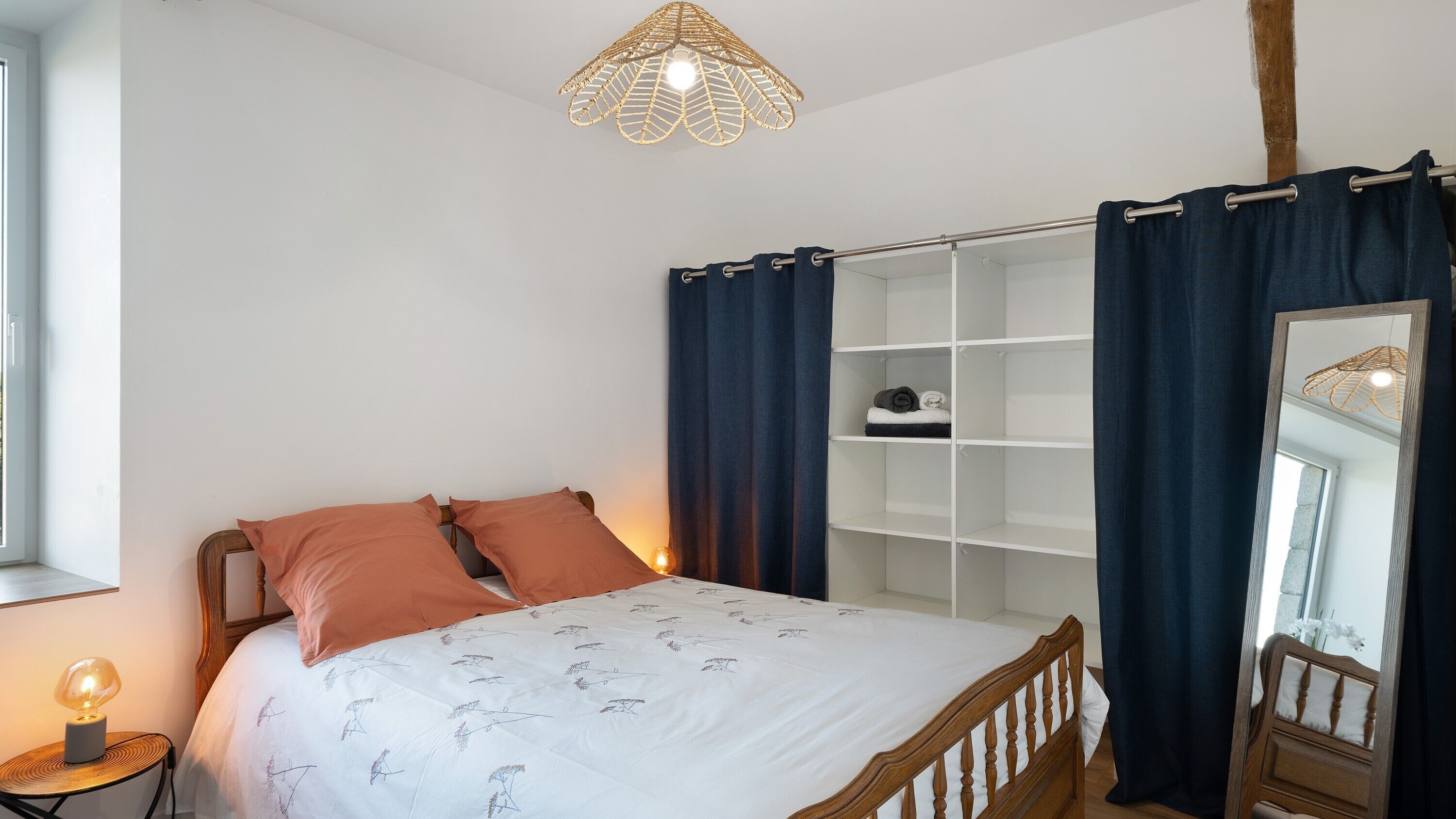 Une chambre à coucher avec un lit, une table de chevet avec une lampe, une armoire et un miroir.