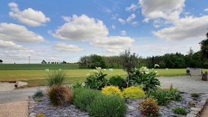 A landscaped garden with a stone pathway, various plants, and hay bales in the background. - Gîte - Le Buis de Bréhaut: terrace, garden, and Wi-Fi (Taupont)