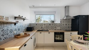 Una cocina moderna con baldosas estampadas, un refrigerador negro y una ventana con vistas.