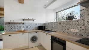 A modern kitchen with a washing machine, dishwasher, and a microwave.