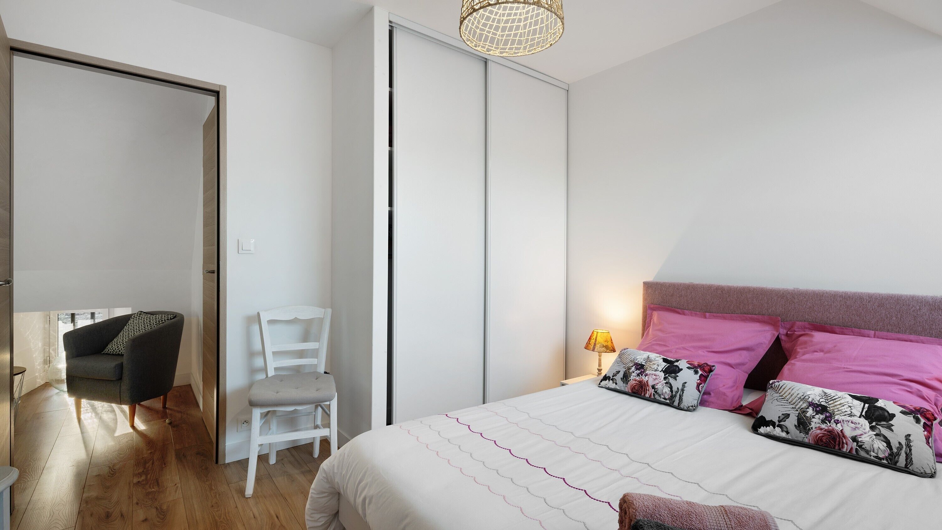 Un dormitorio con cama, una silla, un escritorio y un armario.