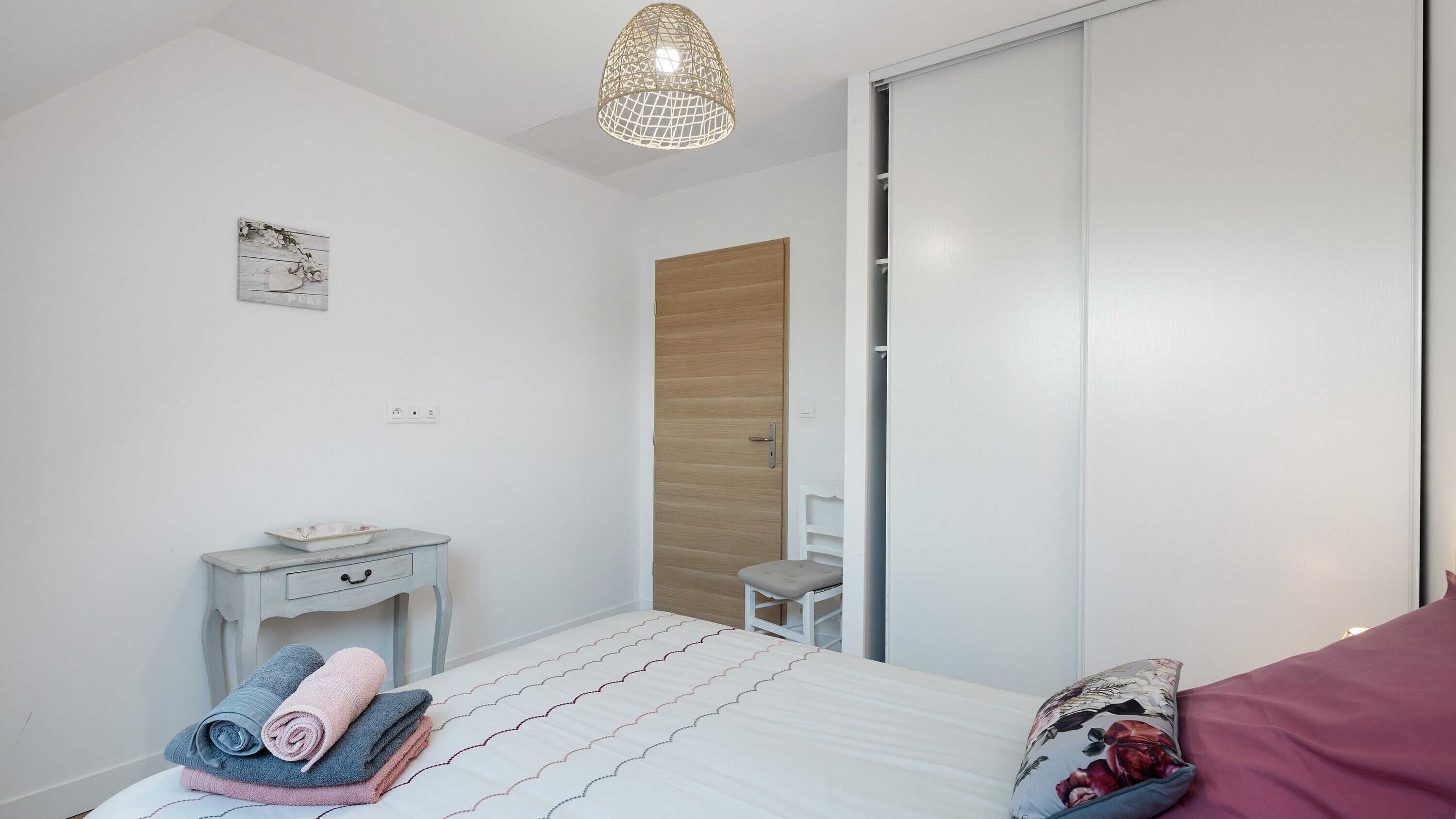 Ein Schlafzimmer mit Bett, Nachttisch, Stuhl und Kleiderschrank.