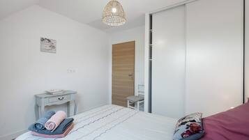 Ein Schlafzimmer mit Bett, Nachttisch, Stuhl und Kleiderschrank.
