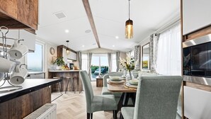 Una cucina moderna con zona pranzo, caratterizzata da un piano di lavoro in legno, una lampada a sospensione e vista sull'esterno.