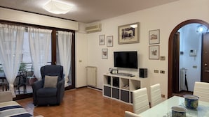 A living room with a sofa, TV, and dining area with chairs and table. - Marci's House (Rome)