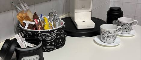 Eine Küchenarbeitsplatte mit Kaffeemaschine, Zuckerbehälter und Tassen.