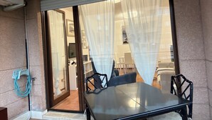 A room with a sliding glass door leading to a balcony, a black table, and two black chairs. - Marci's House (Rome)