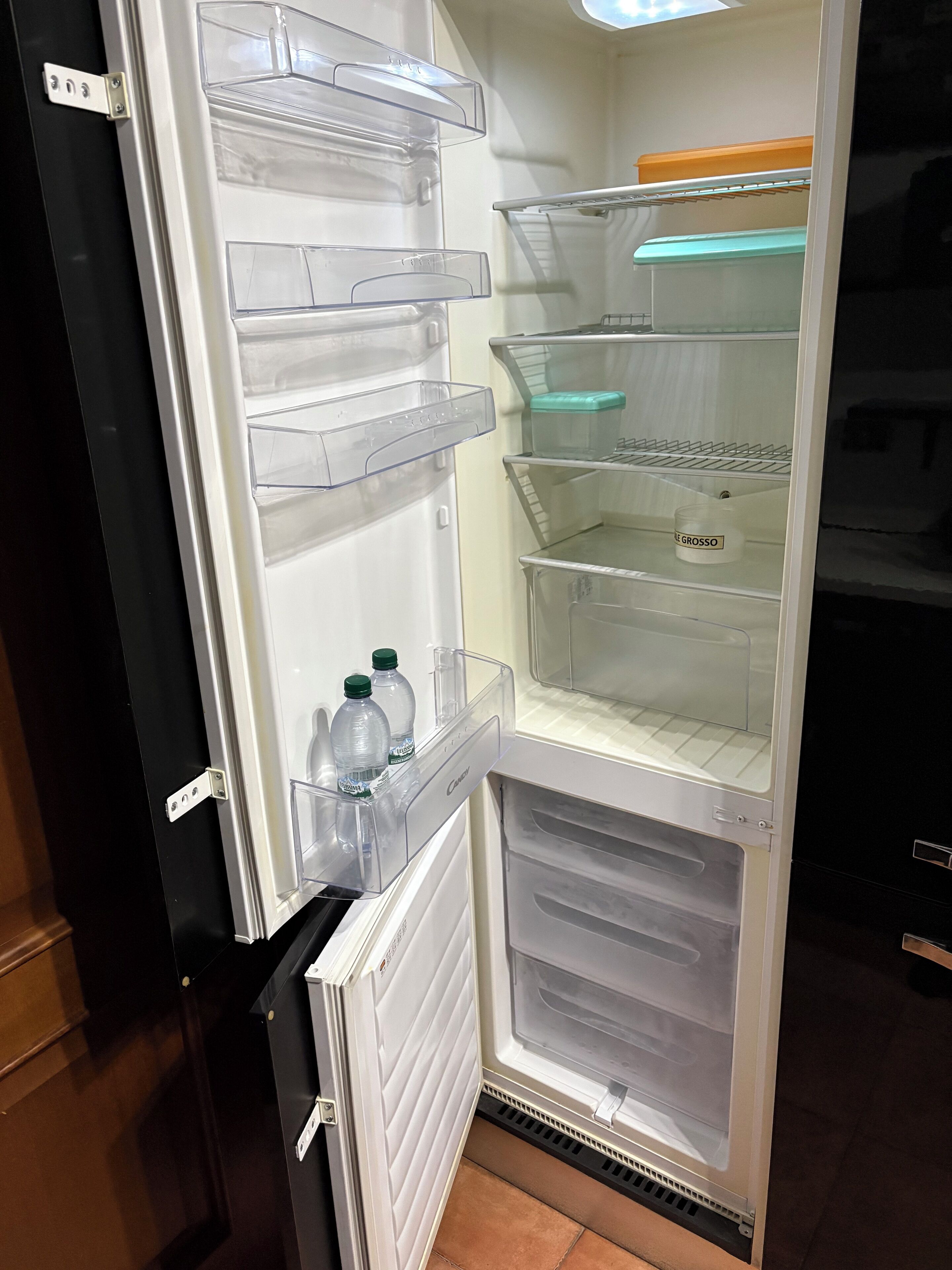 A refrigerator with multiple transparent shelves and a freezer compartment.