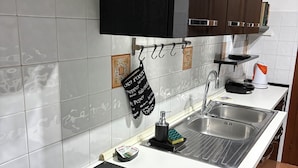 A modern kitchen with a black induction cooktop, a stainless steel sink, and a black hanging pot rack. - Marci's House (Rome)