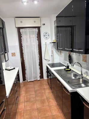 Una cocina con encimera blanca, pileta de acero inoxidable y un reloj en la pared.