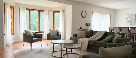 A spacious living room with a sofa, chairs, a coffee table, and a dining area with chairs and a table.
