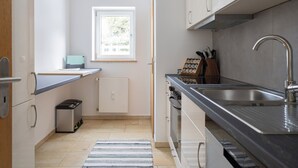 A modern kitchen with a stainless steel sink, a built-in oven, and a window providing natural light.