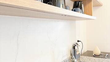 Una cocina con encimera de granito, pileta de acero inoxidable, escurreplatos negro y repisa de madera sobre la encimera.