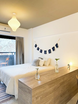 Ein Schlafzimmer mit einem Bett, einem Nachttisch aus Holz, einer Pendelleuchte, einem Fenster mit Vorhängen und einer Wanddekoration.