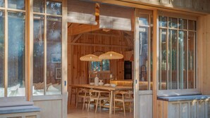 Een houten interieur met een eethoek, grote ramen en een bank.