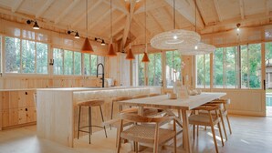 Een ruime keuken met houten kasten, een groot eiland en hanglampen.
