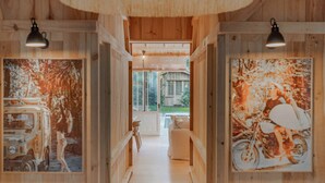 Een houten interieurhal met ingelijste kunstwerken aan de muren, een zitgedeelte in het midden en een uitzicht op de omgeving.