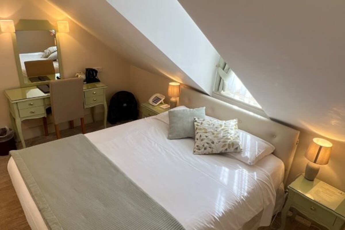 A bedroom with a bed, bedside tables, a desk, a chair, and a mirror.